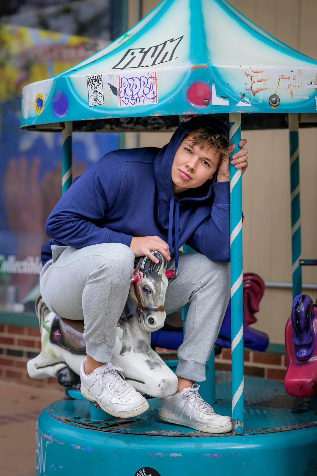 Max Cooper III crouching on a playground carousel horse